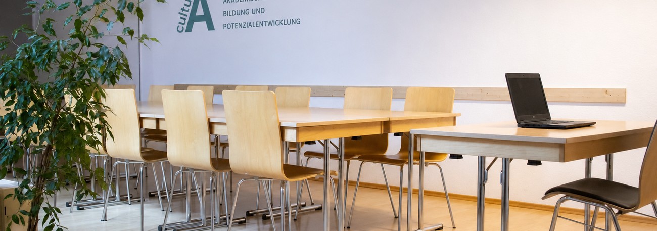 Heller Seminarraum mit Tischen, Stühlen und viel Tageslicht